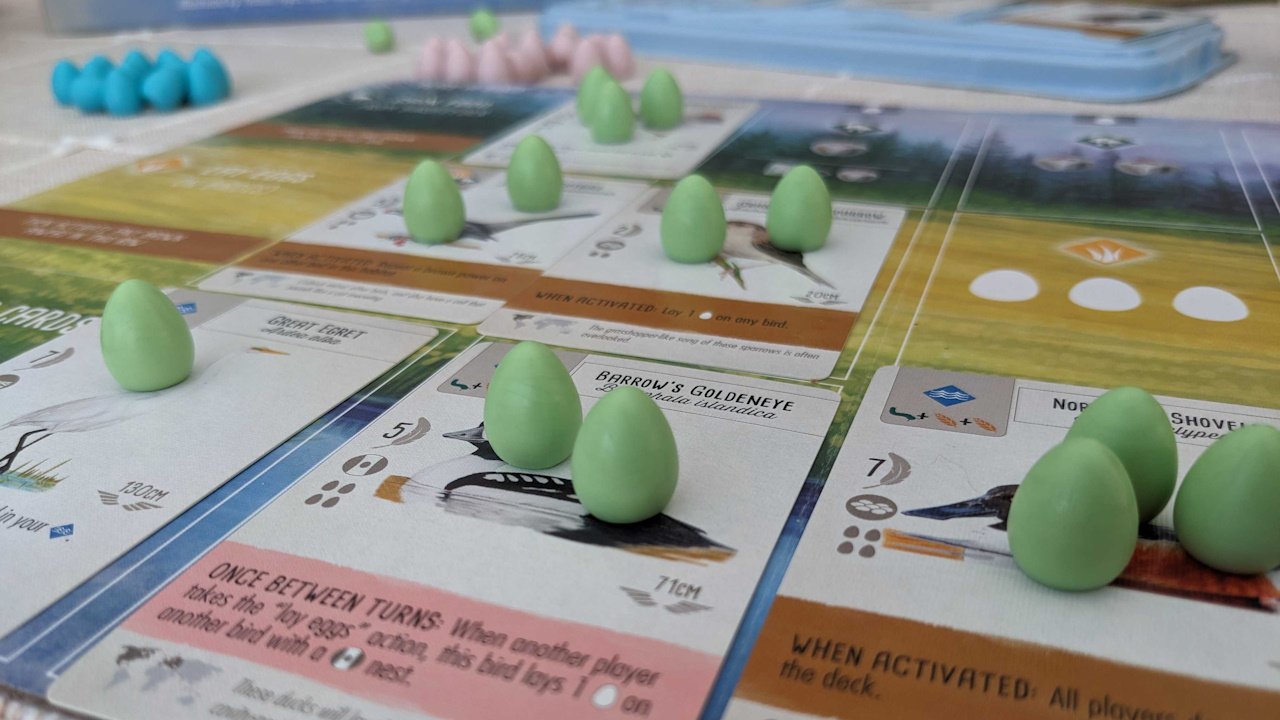 temptingly tasty board game components wingspan - a number of eggs sit atop bird cards in a player's tableau